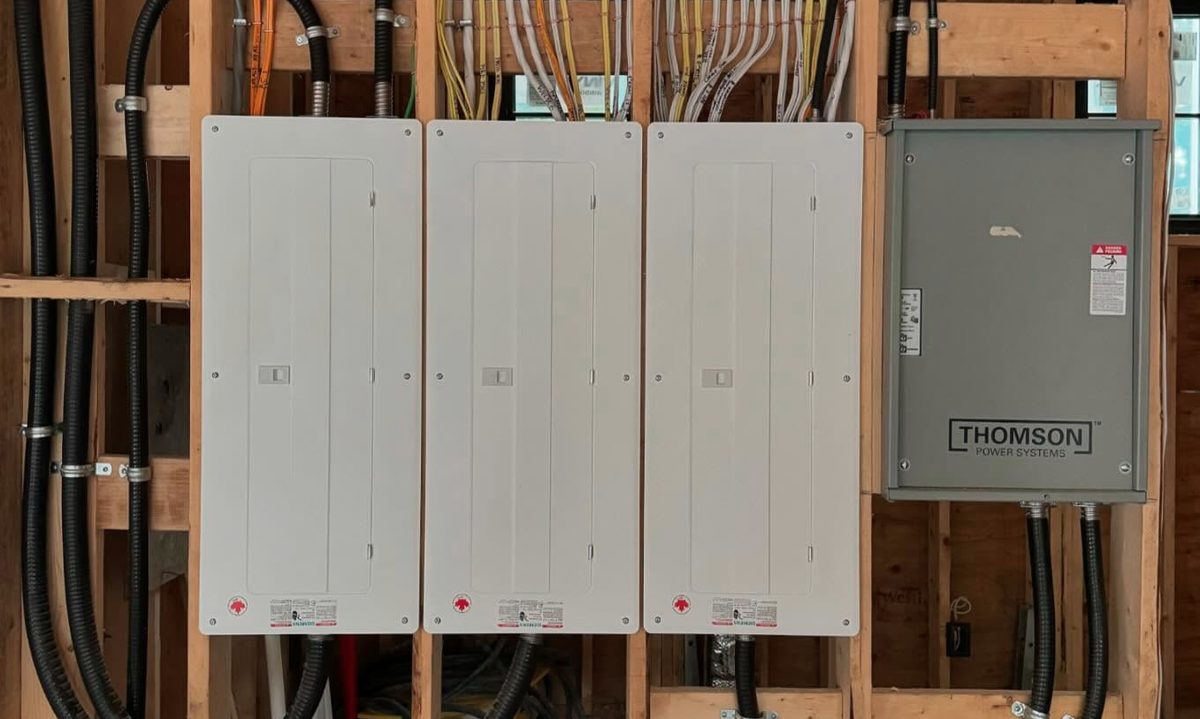 Three neatly installed electrical panels with a Thomson generator transfer system